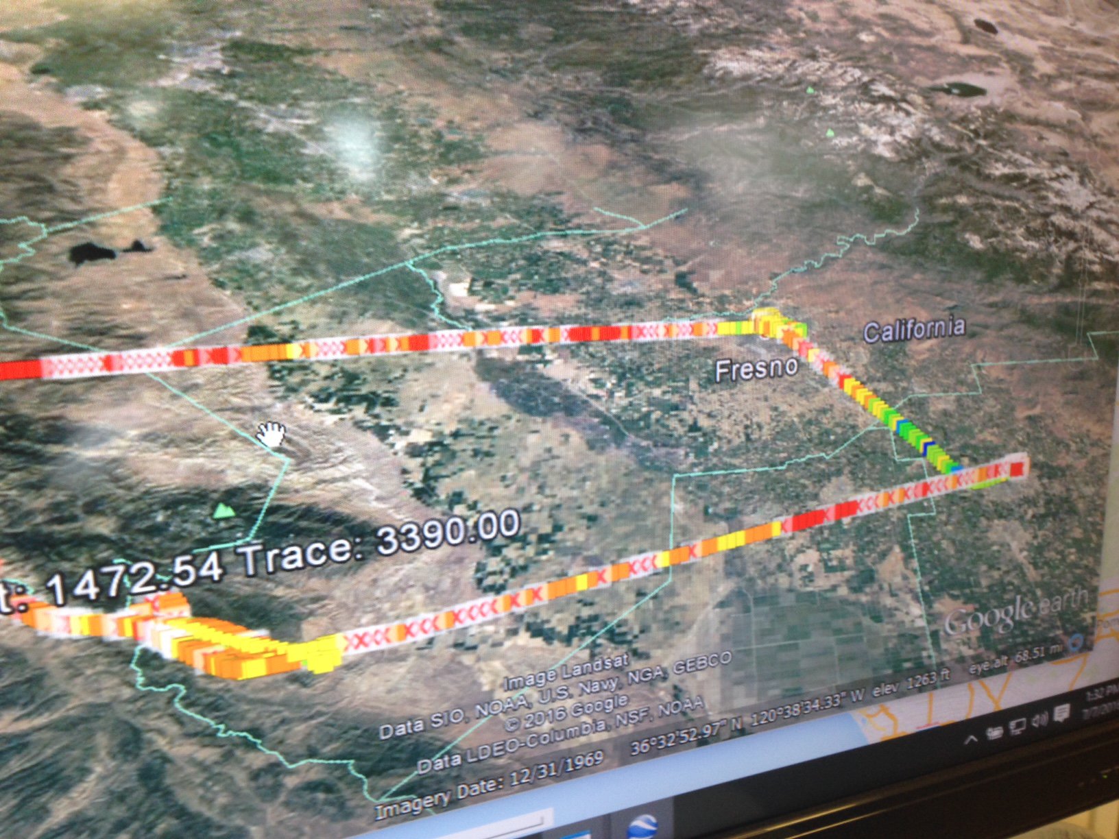 A computer screen is shown with Google Earth open on the screen. Satellite imagery of the California Central Valley is visible, overlain with lines that are colored various shades of red, orange, yellow, and green, with the color of each line changing many times.