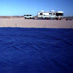 The two tarps were set up with a series of small white flags at regular 10m intervals between them, marking off ten AirMISR pixels as projected on the ground from the 20km altitude of the ER-2.  The reflectance of each pixel-sized area between the tarps was determined for later comparisons to the values of actual AirMISR image pixels. The right pixels to use are picked out from the scene by looking for the tarps (a couple of darker pixels) in the image and selecting those image pixels between them.  Photo taken from southern edge of south tarp looking north.